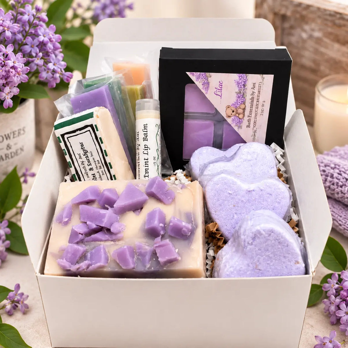 Open spa gift box with lilac soap bars, heart bath bombs, and bath balm