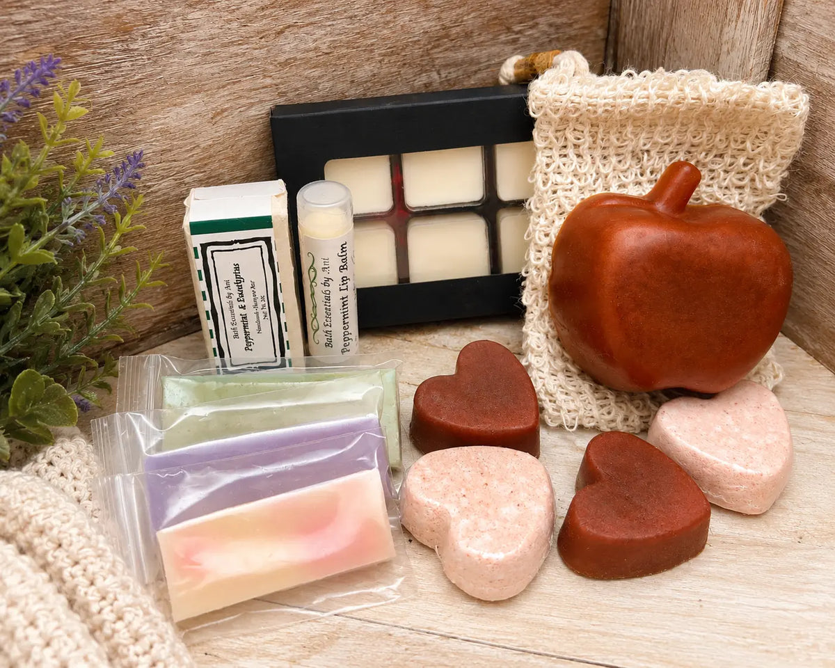 Spa gift set on wooden surface with apple-shaped soap, wax melts, and loofah pouch