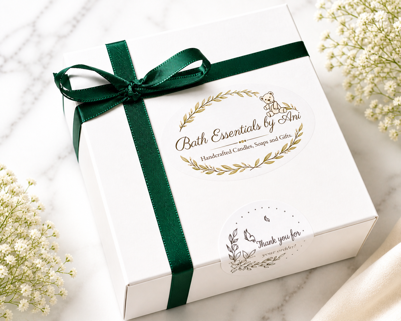 Bath essentials gift box with green ribbon and branded label on white lid