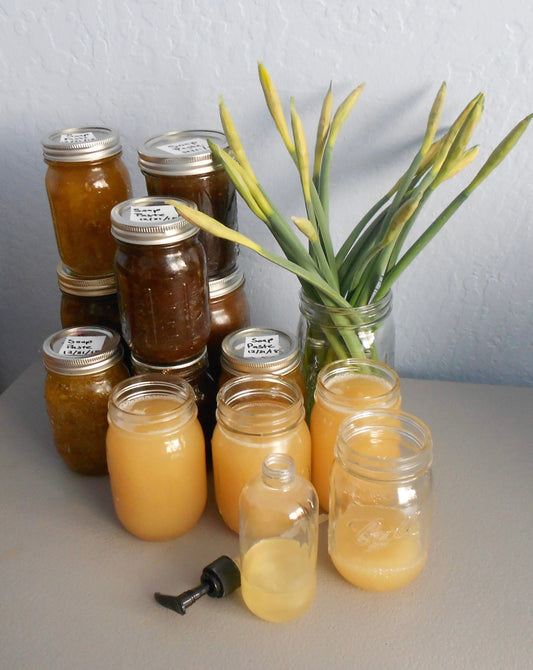 Jars of handcrafted liquid soap paste with flower buds in the background 