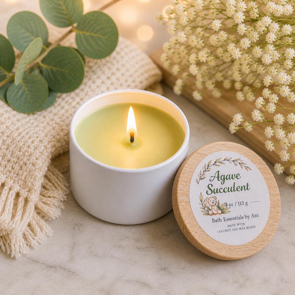 Lit candle in white jar with round wood-lid balm container beside it