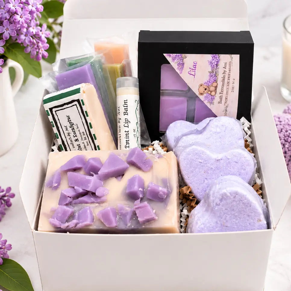 Open spa gift box with lilac soap bars, bath bombs, and assorted wrapped soaps