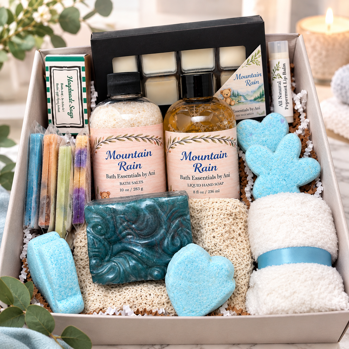 Bath gift box with teal and blue soaps, white scrub pads, and essential oil bottle