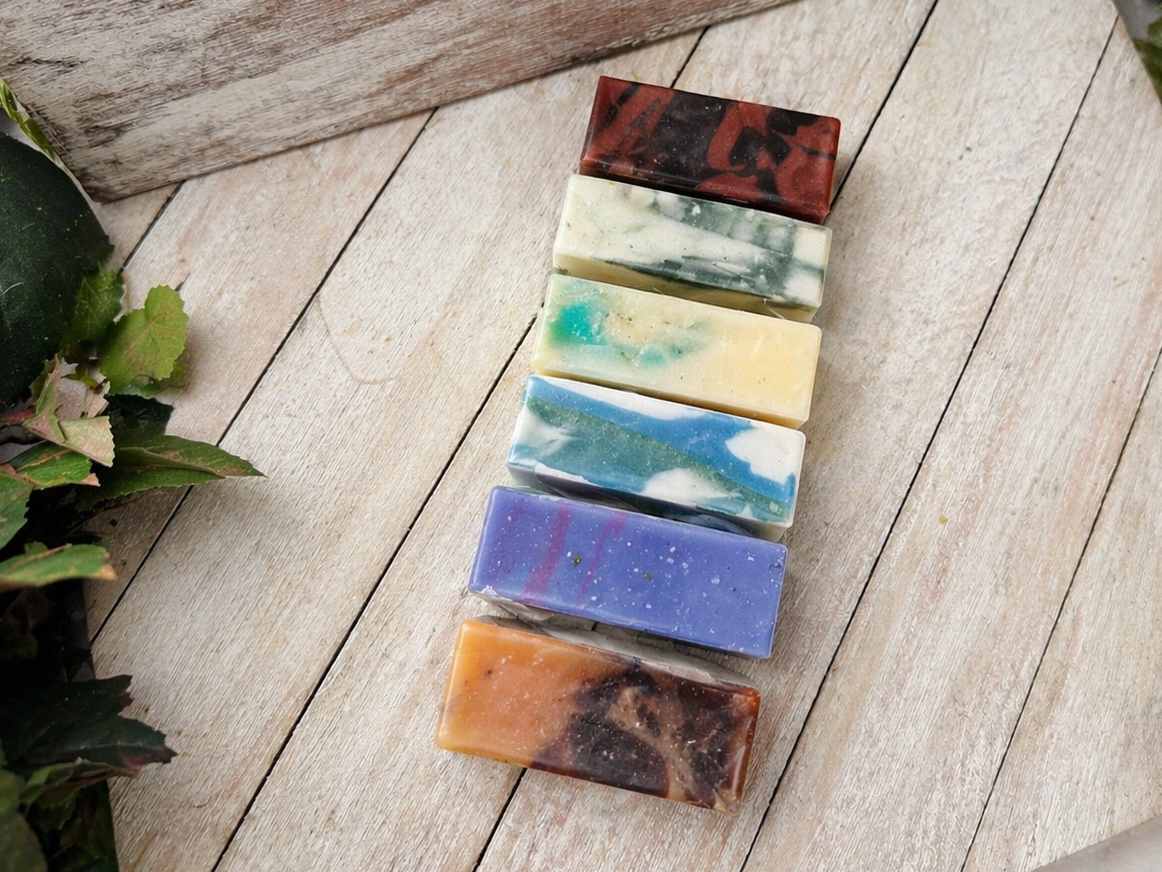 Row of wrapped soap bars on wooden planks, assorted colors in clear packs