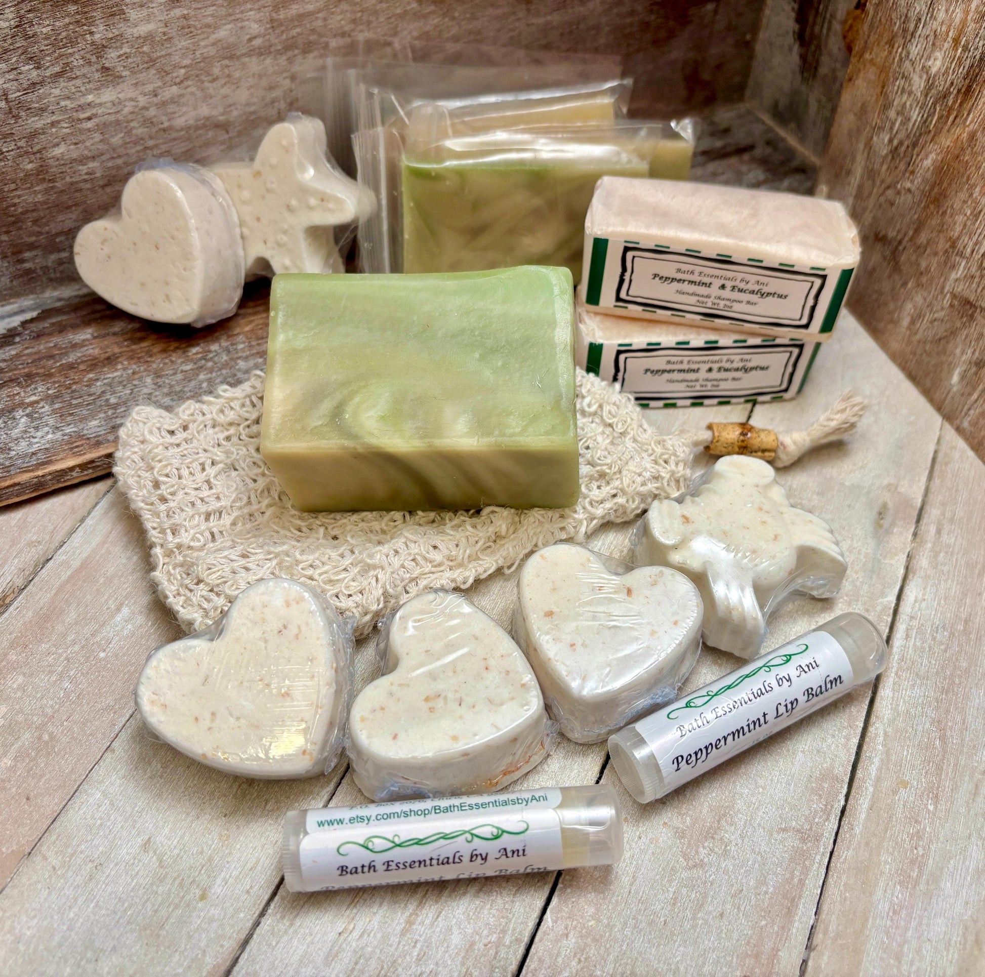 Assorted bath set on wood: green soap bar, white heart fizzies, and lip balm tube