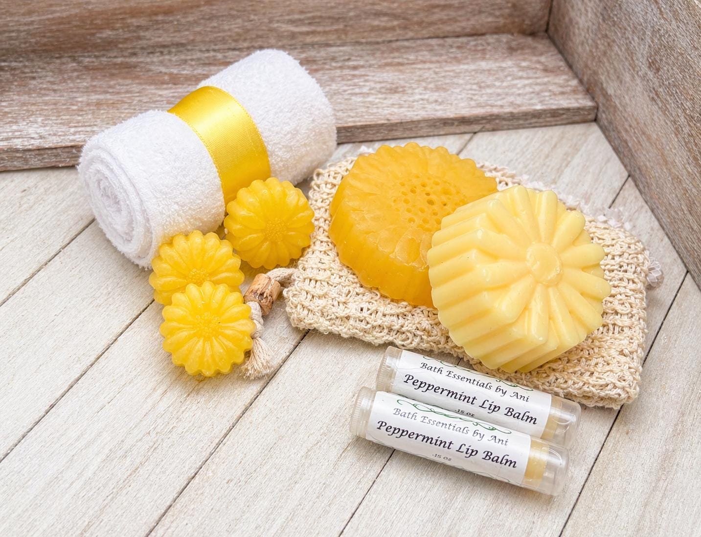 Yellow daisy soap bars with rolled white-and-yellow towels and peppermint lip balm