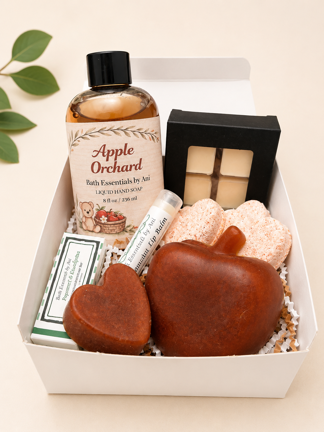 Bath gift box showing two brown heart soaps, liquid hand soap bottle, and pink bath bombs