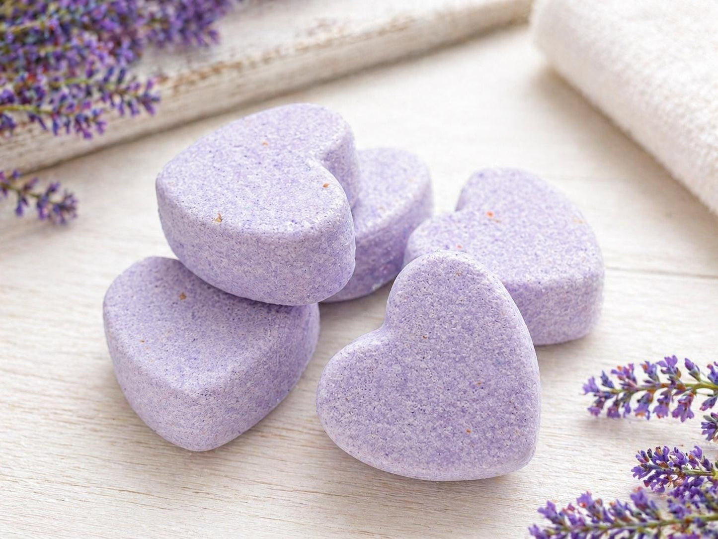Purple heart bath soaps arranged on a light surface with small lavender accents