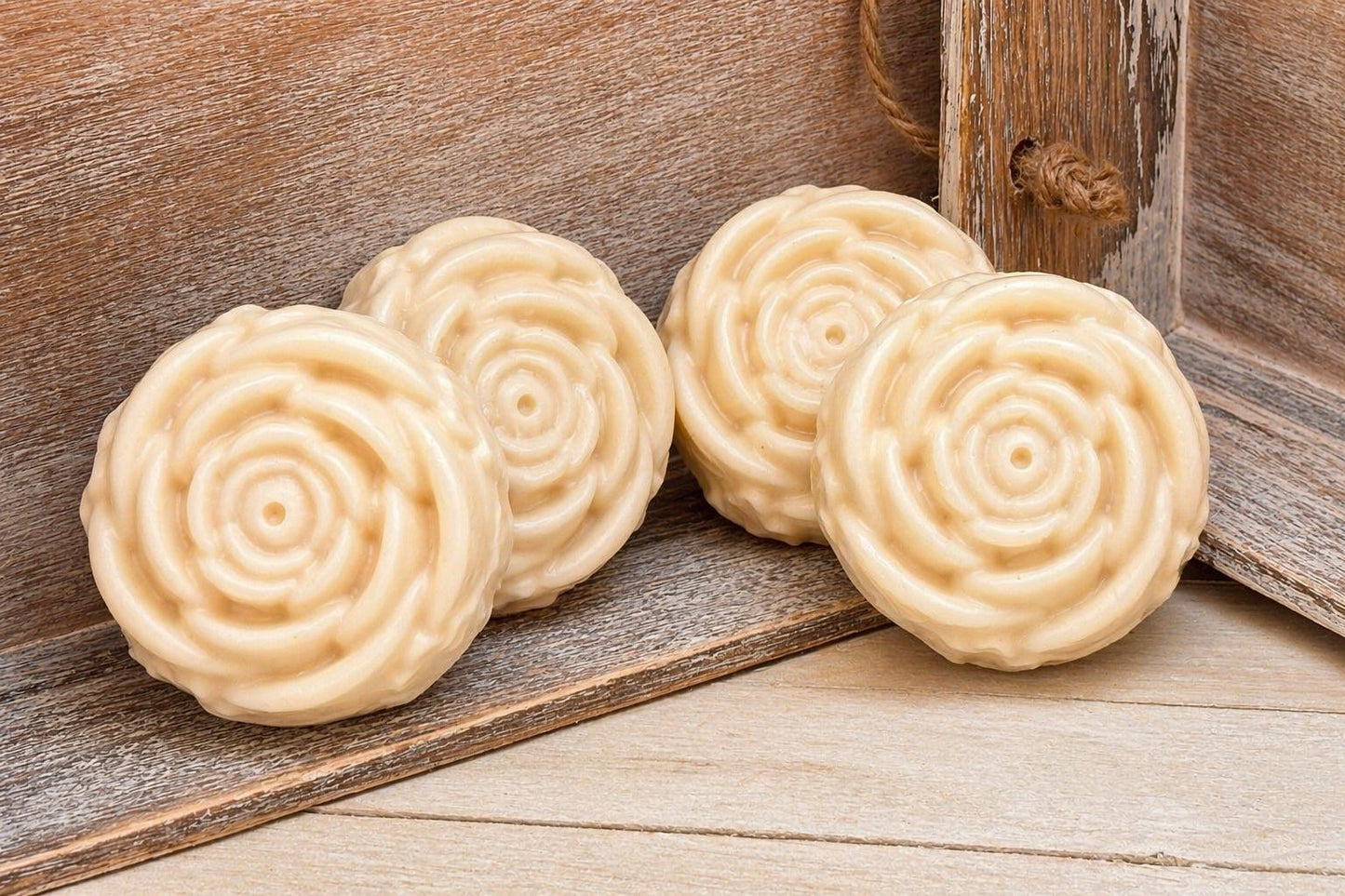 Two round spiral-pattern soaps in pale cream on a wooden surface