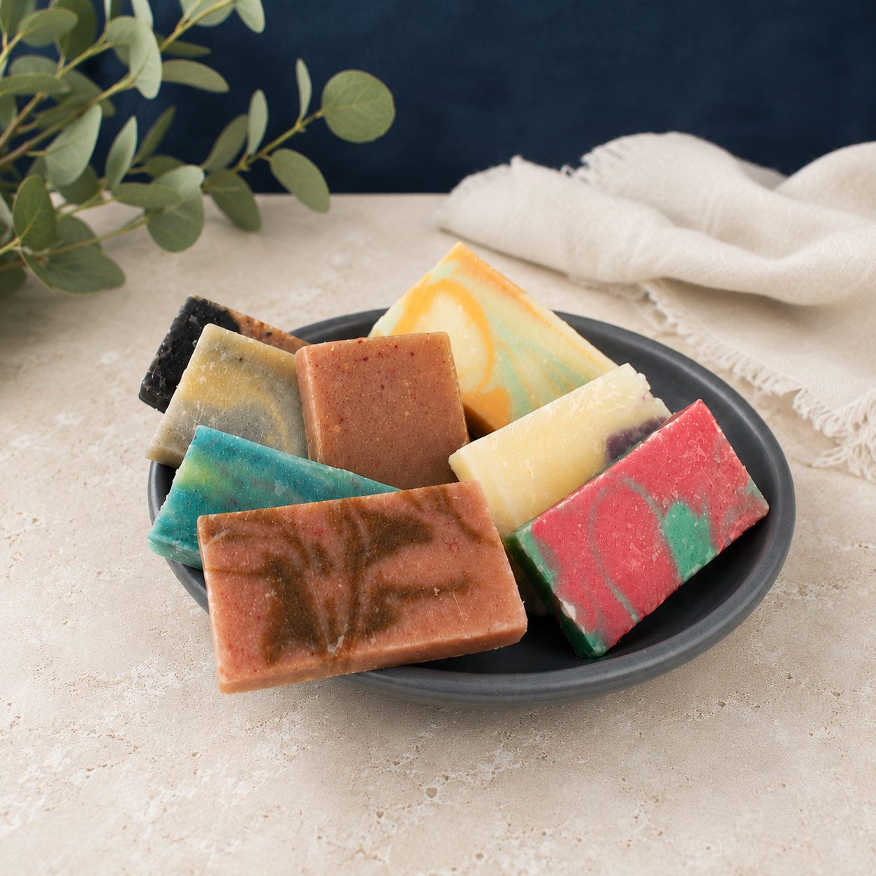 Handmade travel-size soap bars sampler in a black dish, multicolor rectangular bars