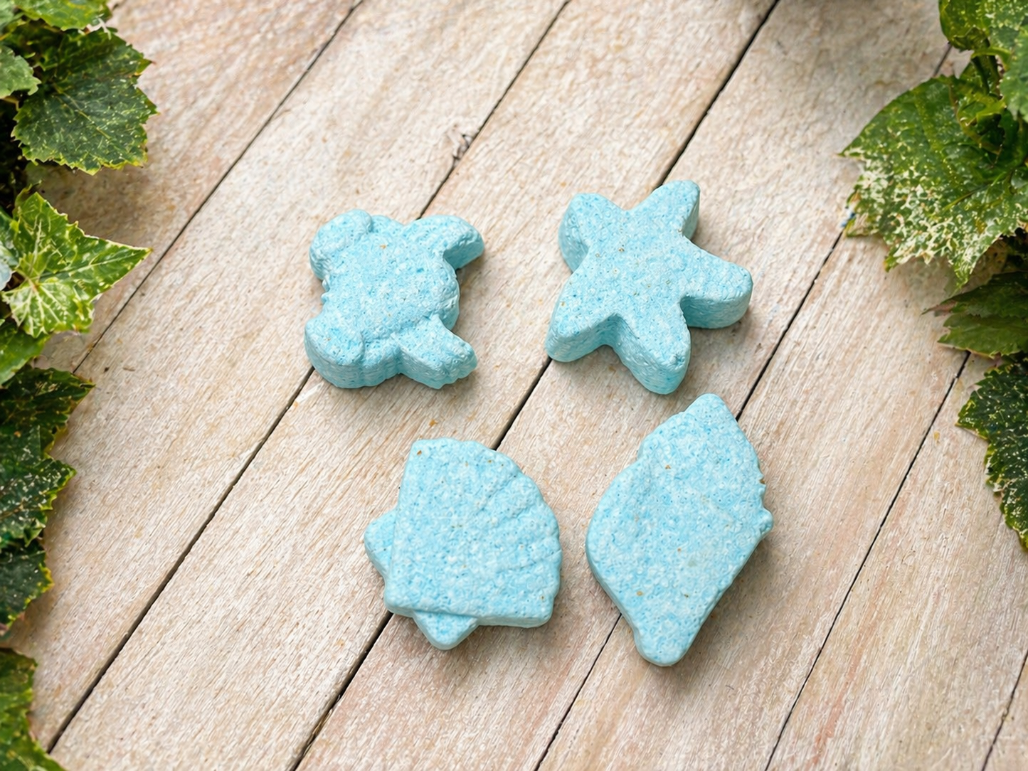 Blue bath bombs in star and flower shapes on a light wood surface