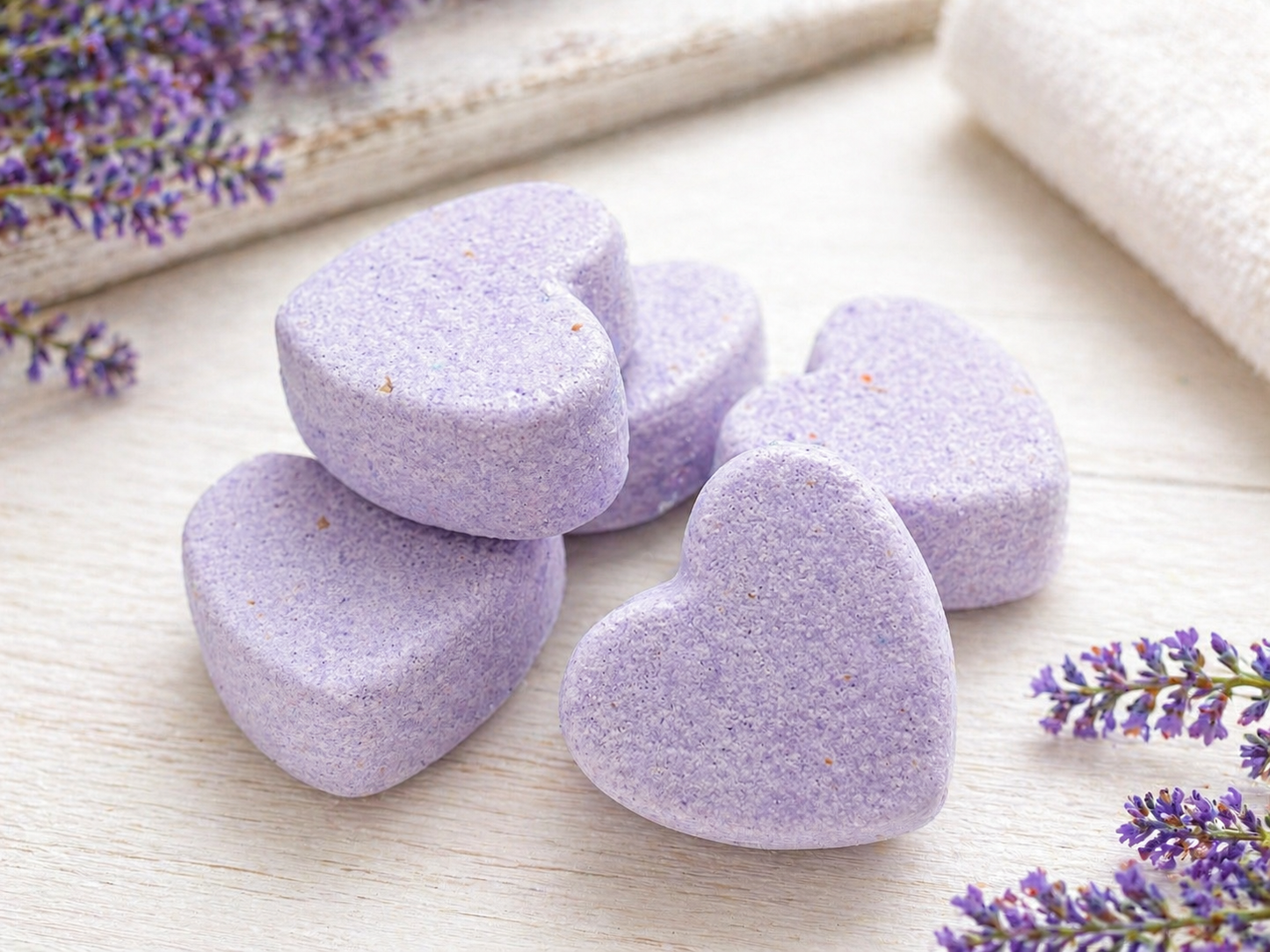 Purple heart-shaped bath bombs with lavender speckles on a light surface