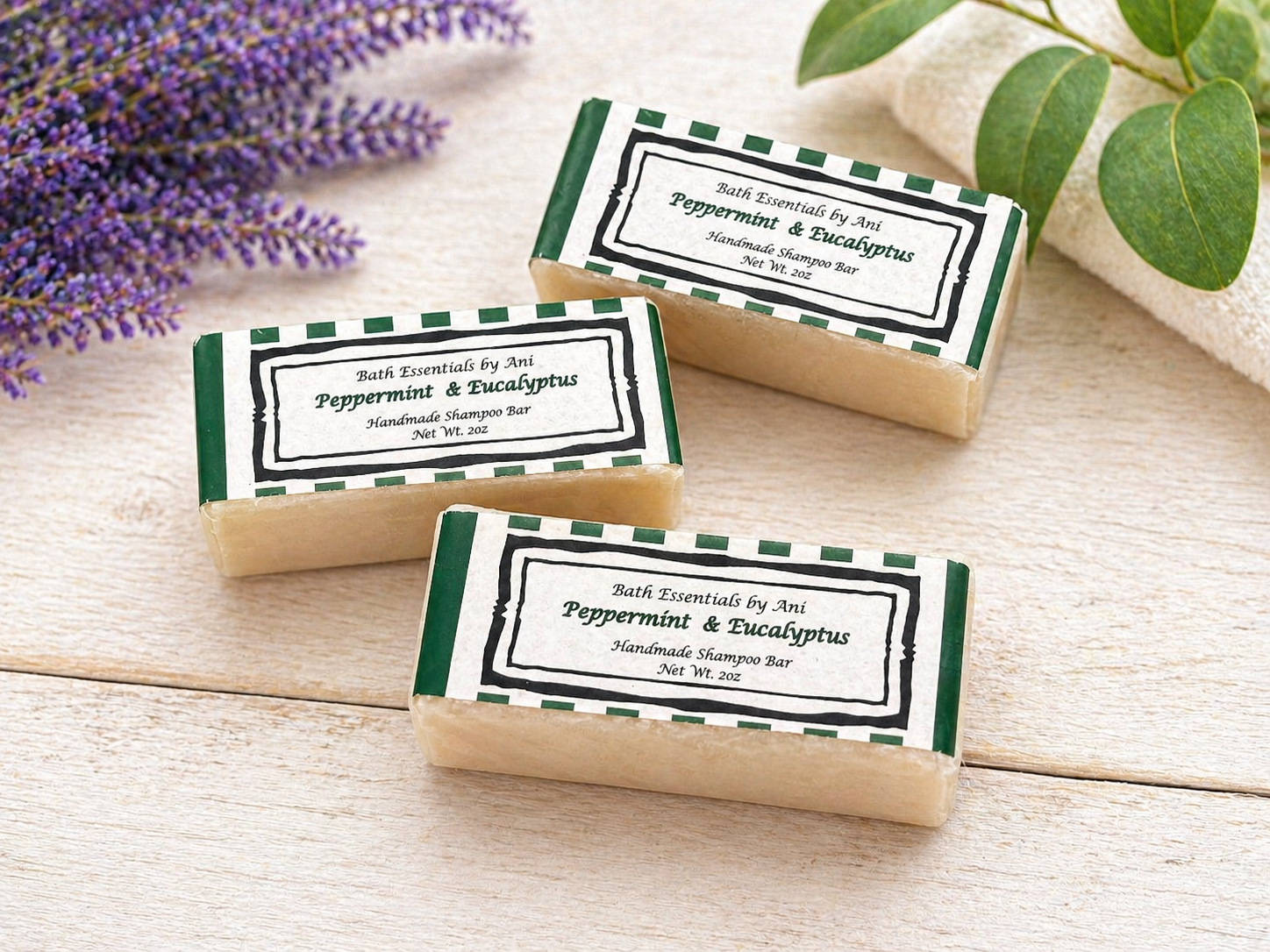 Handmade soap bars with green labels and a tan base on a wooden surface
