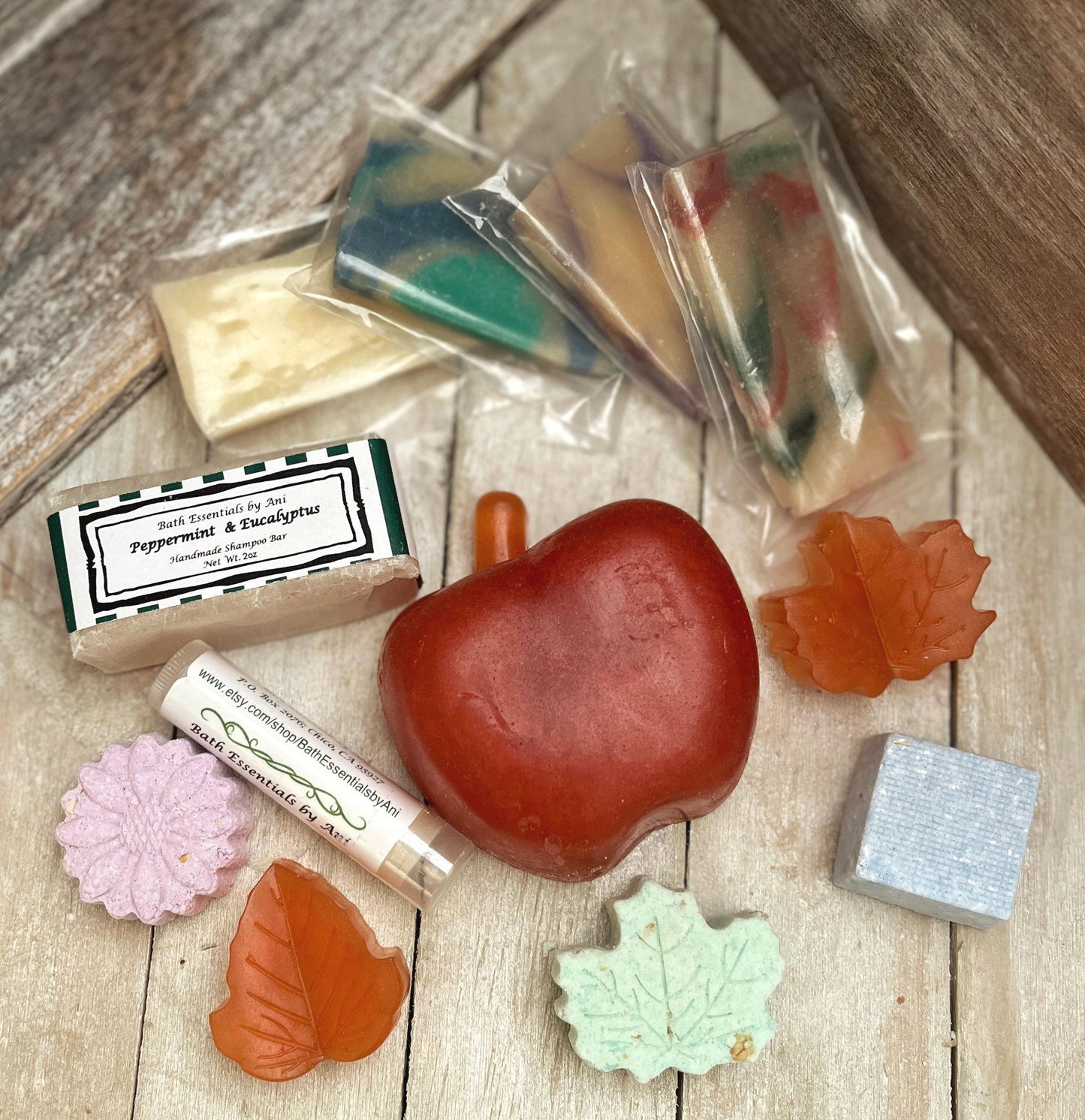 Bath soap bar and lip balm pieces with small boxed soaps on wooden surface