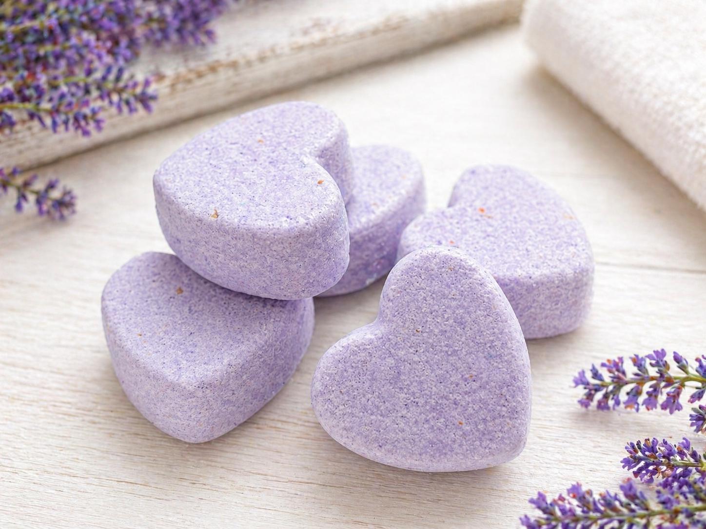 Lavender heart bath bombs, five heart-shaped pieces on a light wood surface