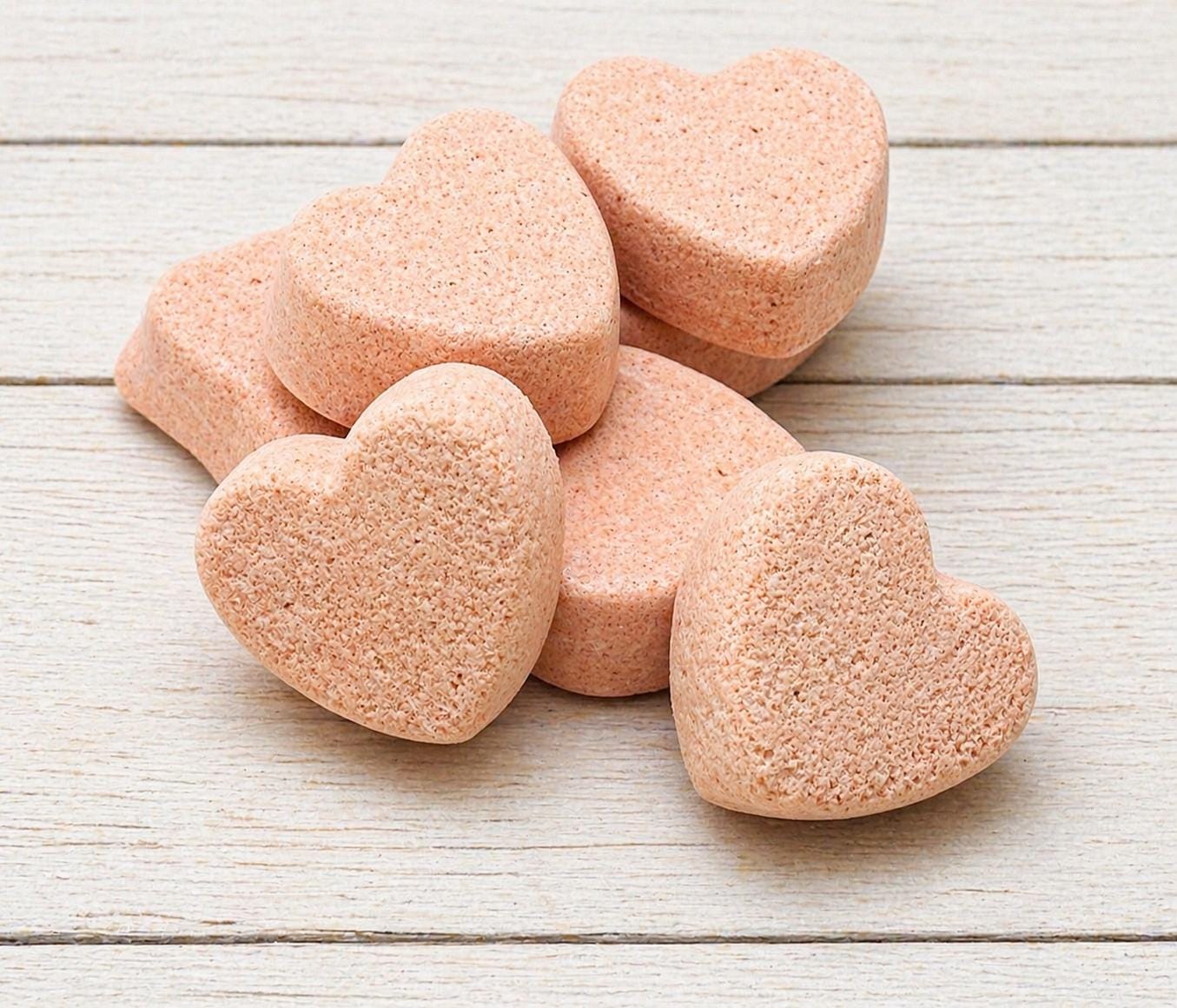 Group of beige heart-shaped bath bombs on light wood surface