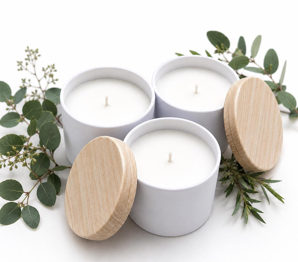 Set of three white coconut soy candles in round tins with bamboo-style wooden lids